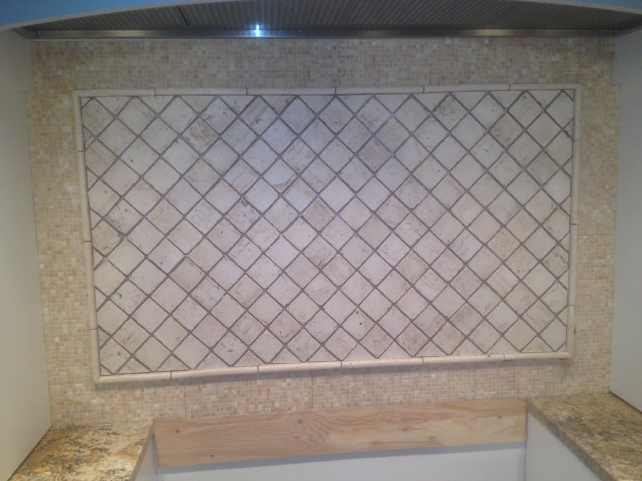 Kitchen range backsplash with a diagonal tile inset framed by a mosaic border beneath the hood