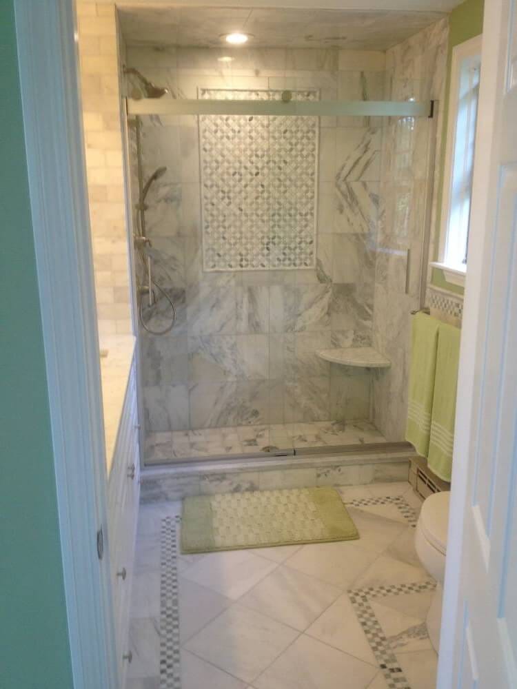 Finished tiled shower with a framed patterned panel, corner bench and coordinating bathroom floor border